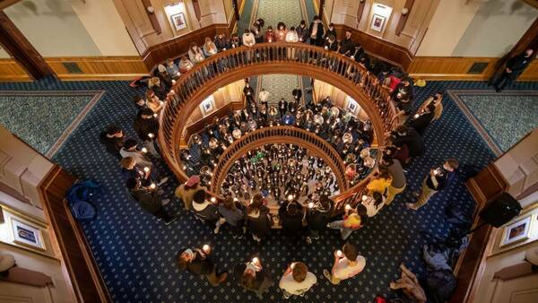 Overhead view of the rotunda in the Main Building where dozens of people hold candles