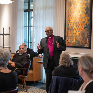Bishop Curry stands in front of a room full of people and talks