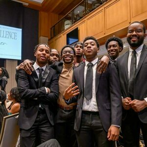 A group of young black men in suits pose for a group photo