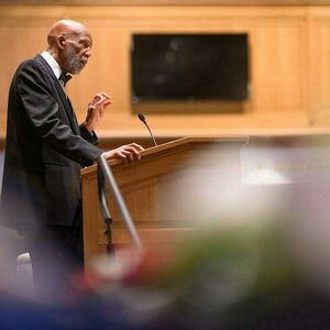 Dr. Terrence Roberts, an African American man wearing a suit and bow-tie speaks while at a podium